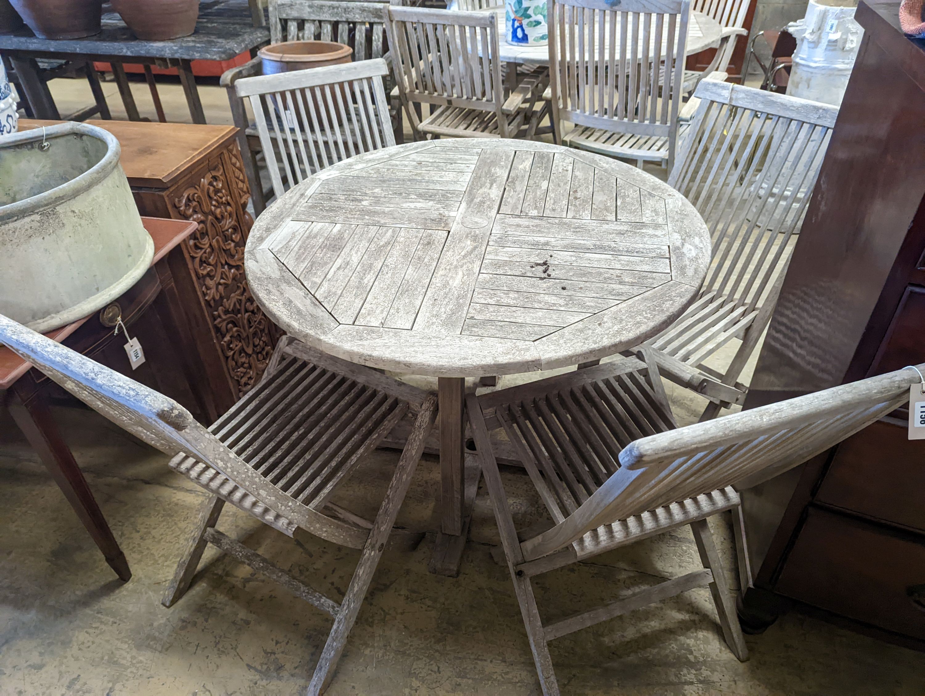 A circular weathered teak garden table, diameter 100cm, height 75cm together with four folding chairs